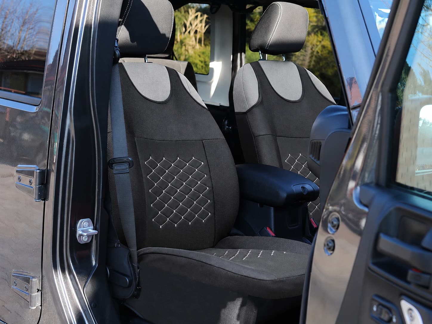 Motive T-shirt autostoelhoezen zwart met grijze stiksels gemonteerd op de voorstoelen van een auto